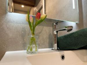 a vase with flowers in it sitting on a sink at Leogang apartment with mountain views in Leogang +32 photos