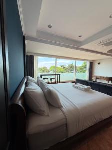 a bedroom with a large bed with a large window at Gooseberry Baan & Bistro in Pattaya South