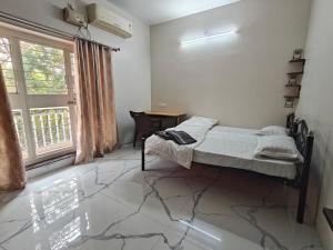 a bedroom with a bed and a desk and a window at Elegant 2 BHK Furnished flat without AC and with AC additional price in Belgaum