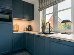 a kitchen with blue cabinets and a sink and a window at Dorfhüs 1 in Tinnum +27 photos