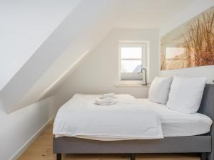 a bedroom with a bed with white sheets and a window at Dorfhüs 1 in Tinnum