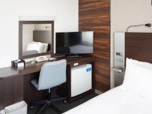 a hotel room with a desk with a television and a bed at Comfort Hotel Tokyo Higashi Nihombashi in Tokyo +29 photos
