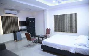 a bedroom with a bed and a table and chairs at Highway Grand Residency in Hyderabad