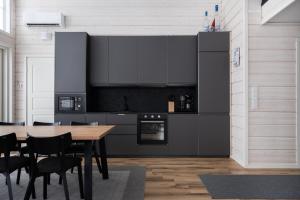 a kitchen with a wooden table and black appliances at Villa Taalontuuli Aurora & Forest Views sleeps 10 in Kittilä +16 photos