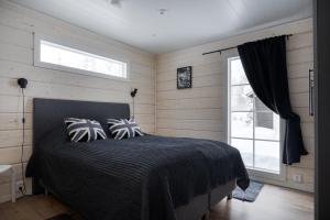 a bedroom with a bed with a black comforter and a window at Villa Taalontuuli Aurora & Forest Views sleeps 10 in Kittilä