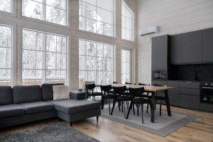 a living room with a couch and a table and chairs at Villa Taalontuuli Aurora & Forest Views sleeps 10 in Kittilä