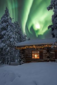 a cabin in the snow with the aurora in the sky at Saariselkä Kelo Lodge in Saariselka