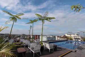 a balcony with chairs and a swimming pool and palm trees at Hotel FortunaGrande Malioboro Yogyakarta in Yogyakarta