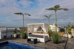 a canopy bed on the roof of a building with palm trees at Hotel FortunaGrande Malioboro Yogyakarta in Yogyakarta