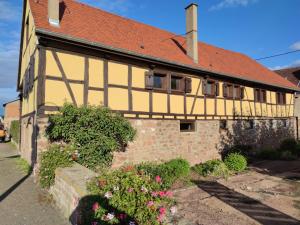 a yellow building with a red roof and some flowers at Fank'House in Guémar