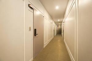 a hallway with white walls and a long hallway with a door at ZaZa HOTEL in Bucheon