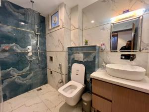 a bathroom with a toilet and a sink and a mirror at Shivalaya Suites in Pātan