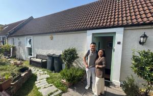 a man and woman standing in front of a house at COSY COTTAGE FOR SHARE , Private Double Room, Wifi, Parking, Garden in Edinburgh