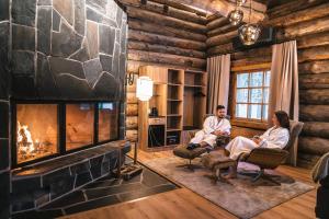a man and woman sitting in a living room with a fireplace at Saariselkä Kelo Lodge in Saariselka