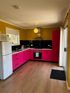 a kitchen with red cabinets and a white refrigerator at Bruny Seaview Escape in Alonnah
