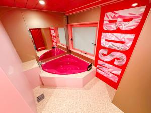 a bathroom with a pink tub in a room at Fire Hotel Nw in Saitama