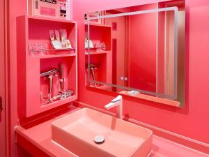 a red bathroom with a sink and a mirror at Fire Hotel Nw in Saitama