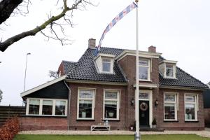 a house with a flagpole in front of it at Huize Sonnevanck in Sexbierum