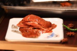 a piece of meat on a white plate on a table at Zhong An Hotel Beijing Former Residence of Journalist Edgar Snow in Beijing