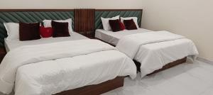 a bedroom with two beds with white and red pillows at Royal Hotel in Begūn