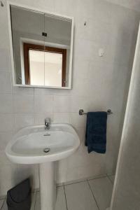a white bathroom with a sink and a mirror at La casa di Lollo in Piombino