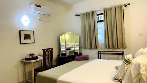 a bedroom with a bed and a desk and a mirror at Oliviana Resort in Bentota