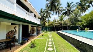 a house with a swimming pool next to a resort at Oliviana Resort in Bentota