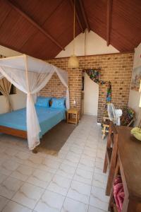 a bedroom with a blue bed and a brick wall at Auberg'inn in Toliara