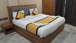a large bed with yellow and white pillows on it at Hotel Vimas International in Madurai