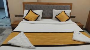 a bedroom with a bed with yellow and white pillows at Hotel Vimas International in Madurai +17 photos