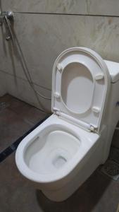 a white toilet with the seat up in a bathroom at Hotel Vimas International in Madurai