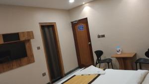 a room with a bed and a door and a table and chairs at Hotel Vimas International in Madurai