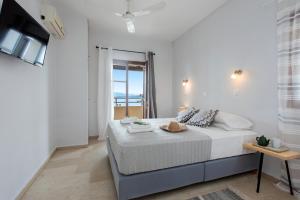 a white bedroom with a bed and a television at Hotel Barbati - Seaside Getaways with Pool in Barbati
