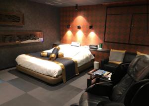 a bedroom with a large bed and two chairs at ホテルアドレリゾート大人専用 in Sendai