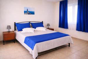 a bedroom with a bed with blue sheets and blue curtains at Apartments Hotel & Studios, Xifoupolis in Monemvasia +66 photos