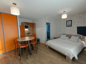 a bedroom with a bed and a table and a kitchen at Appart'Hotel Parc Johan in Chauffailles