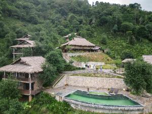 an aerial view of a village with houses and a pond at Ta Xua Ecolodge in Bắc Yên