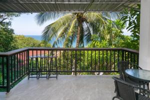 a balcony with chairs and a table and a palm tree at v26 Sunset Dreams - Seaview in Haad Yao in Haad Yao