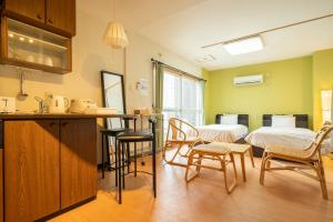 a room with two beds and a kitchen with chairs at Fewdays Condominium608 in Sapporo