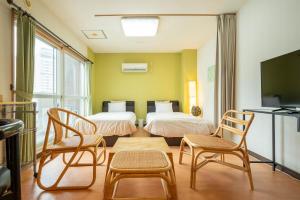 a room with two beds and two chairs and a tv at Fewdays Condominium608 in Sapporo