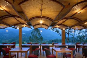 a restaurant with tables and chairs with mountains in the background at Te Dalu Resort & Spa - A Luxury Sanctuary in Ella in Ella