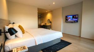a bedroom with a bed with a tv on the wall at Beehive Boutique Hotel Phuket in Phuket