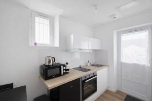 a white kitchen with a microwave and a sink at Le Cocon d'Ezy in Ézy-sur-Eure
