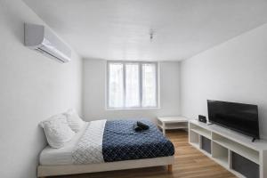 a white room with a bed and a flat screen tv at Le Cocon d'Ezy in Ézy-sur-Eure