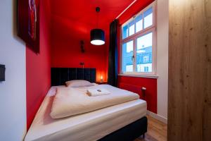 a red bedroom with a bed in a room with a window at Pacmans Penthouse in Leipzig