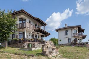 a large white house with a balcony and a house at Balkana Village in Kalaydzhii
