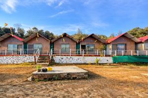 a row of houses in a field with a stone wall at Kedar Avnita Resort in Gupta Kāshi