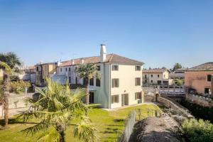 a white house with a palm tree in front of it at "Venetian Elegance Villa" - near Venice historic center in Mira