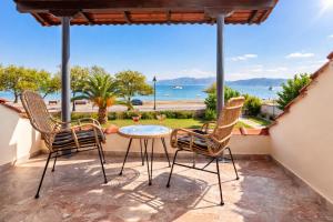 a patio with three chairs and a table with a view of the ocean at Beachfront Villa Psani - Escape with Garden in Nafpaktos