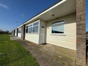 a building with a row of windows and a garage at 116, Two bed Chalet on California Sands Holiday Park - Sleeps 5, pet friendly, includes FREE pool passes, Free Entry to Clubhouse - plus Electric, WiFi, bed linen and towels all included - only 300m from the beach! in Scratby